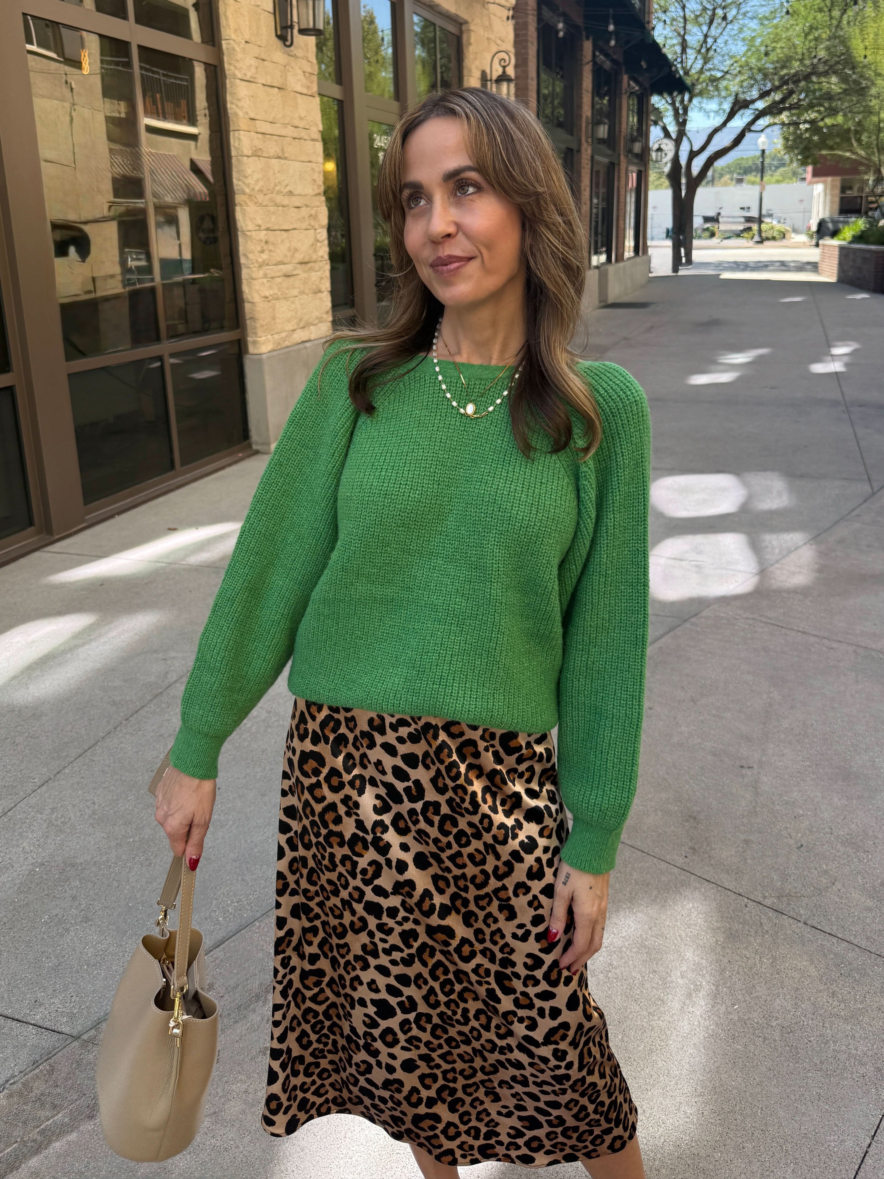 Woman wearing a green sweater and leopard print skirt 