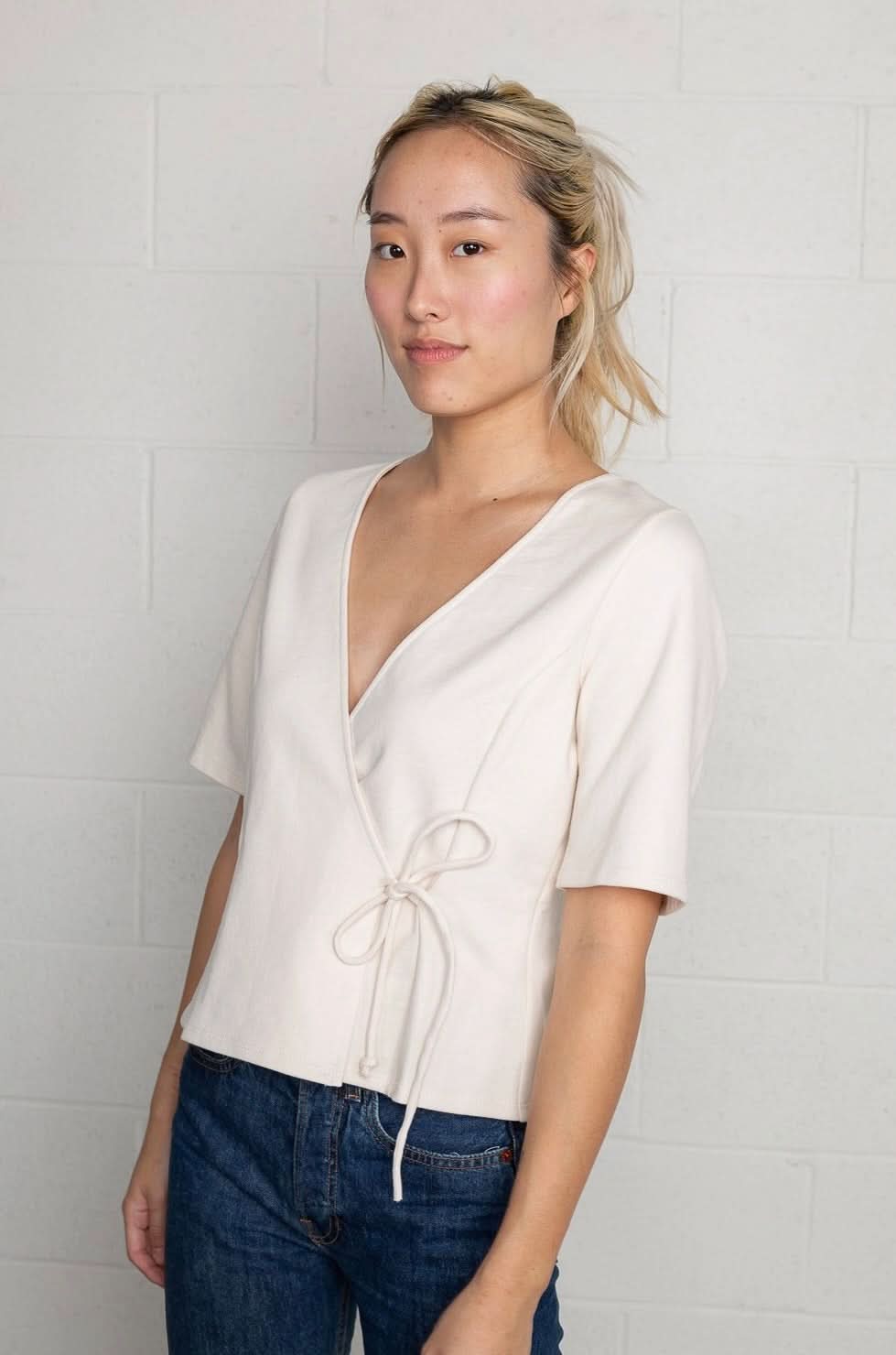 Woman wearing a cream wrap short sleeve shirt with blue jeans